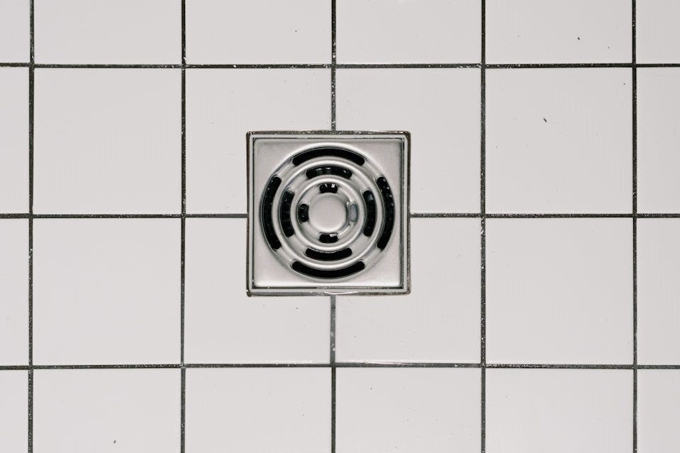 A clean shower drain surrounded by white tile